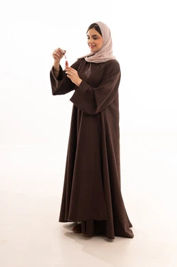 الترويج لمنتجات الشفاه، استخدام المساحيق التجميلية, مفهوم التزين والتجمل,  التسويق لمستحضرات ومنتجات التجميل, الاهتمام والعناية بالمظهر الخارجي,  بورتريه لامرأة عربية خليجية سعودية محجبة ترتدي العباءة السوداء تستعمل أحمر الشفاه, خلفية بيضاء