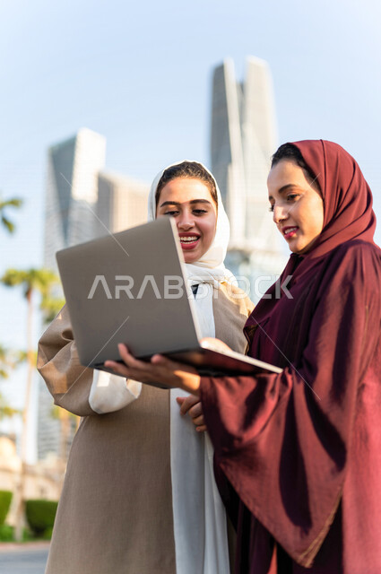 Gulf Saudi Arabian businesswomen using laptop computers in King Abdullah Financial District, Kafed in Riyadh, Kingdom of Saudi Arabia, discussing a work project, field study, remote work