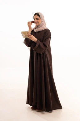 التسويق لمستحضرات ومنتجات التجميل, الاهتمام والعناية بالمظهر الخارجي, استخدام المساحيق التجميلية, مفهوم التزين والتجمل, بورتريه لامرأة عربية خليجية سعودية محجبة ترتدي العباءة السوداء تستعمل فرشاة أحمر الخدود, شابة سعودية تضع المكياج, خلفية بيضاء