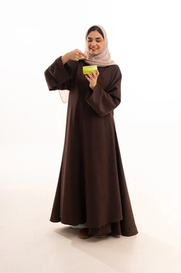 استخدام أفضل الكريمات، استخدام المساحيق التجميلية, مفهوم التزين والتجمل,  التسويق لمستحضرات ومنتجات التجميل, الاهتمام والعناية بالمظهر الخارجي,  بورتريه لامرأة عربية خليجية سعودية محجبة ترتدي العباءة السوداء تستعمل كريم مرطب, خلفية بيضاء