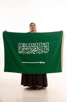 المشاركة الأعياد الوطنية، اليوم الوطني السعودي، بورتريه لامرأة عربية خليجية سعودية محجبة مبتسمة ترتدي الحجاب وترفع علم السعودية بايماءات الفخر والاعتزاز بالوطن، يوم العلم السعودي 11 مارس، العيد الوطني 23 سبتمبر، صورة الجسم بالطول الكامل، خلفية بيضاء