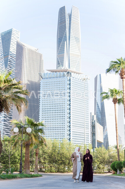 سيدتان عربيتان خليجيتان سعوديتان تتحدثان مع بعضهما البعض ، التجول في مدينة الملك عبد الله المالية كافد في مدينة الرياض في المملكة العربية السعودية ،العلاقات الاجتماعة و الصداقات ، لقاءات تعريفية نسائية ، نزهة في حدائق المملكة العربية السعودية