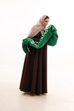 تقبيل العلم الوطني، الاحتفال بالمناسبات الوطنية، الفخر و الاعتزاز بالانتماء للوطن، استذكار اليوم الوطني السعودي 23 سبتمبر، يوم العلم 11 مارس، رفع راية التوحيد والإسلام، بورتريه لامرأة عربية خليجية سعودية محجبة تحمل بيدها علم السعودية ، الطول الكامل للجسم، خلفية بيضاء