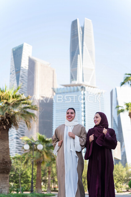 سيدتان عربيتان خليجيتان سعوديتان تتحدثان مع بعضهما البعض ، التجول في مدينة الملك عبد الله المالية كافد في مدينة الرياض في المملكة العربية السعودية ،العلاقات الاجتماعة و الصداقات ، لقاءات تعريفية نسائية ، نزهة في حدائق المملكة العربية السعودية