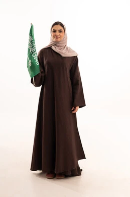 Commemoration of the Saudi National Day on September 23, Flag Day on March 11, celebration of national occasions, raising the banner of monotheism and Islam, a portrait of a Saudi Gulf Arab woman in a hijab holding the green Saudi flag in her hand, pride and honor in belonging to the homeland, full-body image, white background.