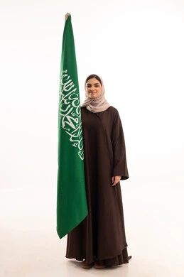Celebrating national occasions, pride and honor in belonging to the homeland, commemorating Saudi National Day on September 23, Flag Day on March 11, raising the banner of monotheism and Islam, a portrait of a Saudi Arabian Gulf woman in a hijab holding the Saudi flag in her hand, full body length, white background.