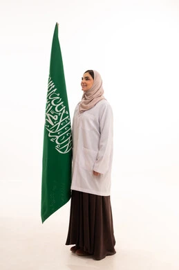 الاحتفال بالمناسبات الوطنية، استذكار اليوم الوطني السعودي 23 سبتمبر، يوم العلم 11 مارس، إعمار البلاد بسواعد ابنائه، رفع راية التوحيد والإسلام، بورتريه لطبيبة عربية خليجية سعودية محجبة ترتدي المعطف الطبي تحمل بيدها علم السعودية ، الطول الكامل للجسم، خلفية بيضاء