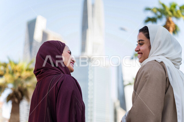 سيدتان عربيتان خليجيتان سعوديتان تتحدثان مع بعضهما البعض ، التجول في مدينة الملك عبد الله المالية كافد في مدينة الرياض في المملكة العربية السعودية ،قضاء وقت ممتع في المدينة المالية