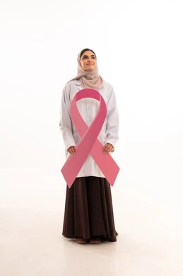 Clarification of the importance of early screening in October, the concept of medicine and healthcare, a portrait of an Arab Gulf Saudi female doctor wearing an abaya and a white coat holding a flag with the breast cancer awareness symbol, a pink ribbon in awareness campaigns, full body length, white background.