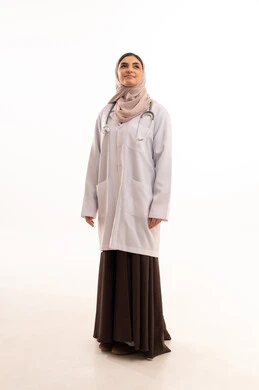 مهن ووظائف نسائية, شابة سعودية تقوم بالعمل في المراكز والمستشفيات,تقديم المساعده الطبية للمرضى,  بورتريه  لطبيبة عربية خليجية سعودية ترتدي المعطف الطبي وسماعة الفحص تقف باستقامة  تنظر إلى الكاميرا بايماءات الثقة بالنفس, خلفية بيضاء