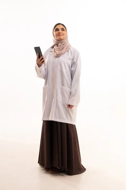 Browsing social media sites via mobile phone, providing therapeutic services in medical centers and hospitals, the concept of medicine and healthcare, a portrait of a veiled Arab Gulf Saudi female doctor wearing a colorful abaya with a medical coat, recording and documenting patient information, full-body image, white background.