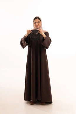 مفهوم العناية والاهتمام بالمظهر الخارجي عند النساء،خطوات تنظيف وتقشير البشرة،استخدام مكون  ومستحضر تجميلي،  بورتريه مقرب لوجه  امرأة عربية خليجية سعودية ترتدي العباءة تقوم يرفع يديها لوضع قناع على وجهها، صورة الجسم بالكامل، خلفية بيضاء