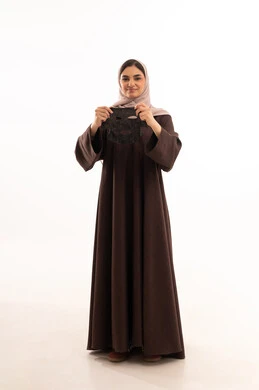 مفهوم العناية والاهتمام بالمظهر الخارجي عند النساء،خطوات تنظيف وتقشير البشرة،استخدام مكون  ومستحضر تجميلي،  بورتريه مقرب لوجه  امرأة عربية خليجية سعودية ترتدي العباءة تقوم يرفع يديها لوضع قناع على وجهها، صورة الجسم بالكامل، خلفية بيضاء