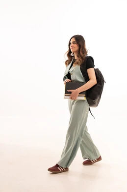 الاستعداد للعام الجامعي الجديد،الجامعات والكليات الأكاديمية،  بورتريه لشابة  جامعية عربية خليجية سعودية ترتدي الزي الكاجوال  تحمل حقيبة الظهر تمسك بيدها الكتب تقوم بمتابعة الدروس اليومية، صورة لكامل الجسم، خلفية بيضاء