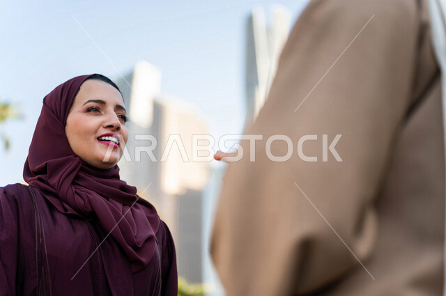 سيدتان عربيتان خليجيتان سعوديتان تتحدثان مع بعضهما البعض ، التجول في مدينة الملك عبد الله المالية كافد في مدينة الرياض في المملكة العربية السعودية ،قضاء وقت ممتع في المدينة المالية