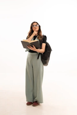 الجامعات والكليات الأكاديمية، الاستعداد للعام الجامعي الجديد، بورتريه لشابة  جامعية عربية خليجية سعودية ترتدي الزي الكاجوال  تحمل حقيبة الظهر تمسك بيدها كتاب تقوم بمتابعة الدروس اليومية، صورة لكامل الجسم، خلفية بيضاء