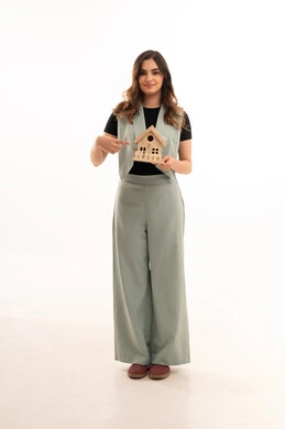 The pursuit of owning a new home, buying and selling real estate, the pursuit of owning a new home, strong family ties, a portrait of a young Arab Gulf Saudi woman wearing casual attire holding a small wooden model of a house with gestures of joy and hope, white background.