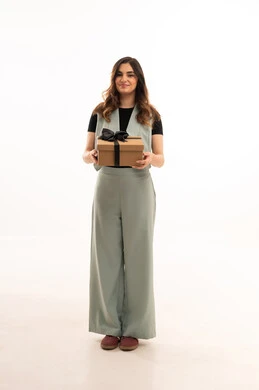 Celebrating Christmas, expressing love and appreciation, giving gifts on happy occasions, a portrait of a Saudi Gulf Arab woman wearing casual clothing holding a gift box in her hands, a young Saudi woman looking at the camera with gestures of happiness and joy, full-body, white background.