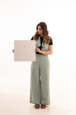 Empty white mockup, marketing display and advertisement, portrait of a smiling Saudi Gulf Arab woman wearing casual attire holding a blank rectangular white board in her hands, full body, white background.