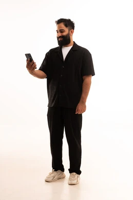 بورتريه لرجل عربي خليجي عماني يرتدي الزى الكاجوال  يمسك الهاتف المحمول بيده ،استخدام التقنيات والتكنولوجيا الحديثة والمتطورة، إيماءات السعادة بسماع أخبار جيدة،  الجسم بالطول الكامل، خلفية بيضاء