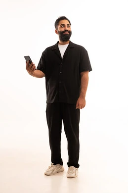إيماءات السعادة بسماع أخبار جيدة، استخدام التقنيات والتكنولوجيا الحديثة والمتطورة، بورتريه لرجل عربي خليجي عماني يرتدي الزى الكاجوال  يمسك الهاتف المحمول بيده ، الجسم بالطول الكامل، خلفية بيضاء