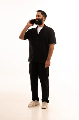 The use of modern and advanced technologies, gestures of happiness upon hearing good news, a portrait of an Arab Gulf Omani man wearing casual attire holding a mobile phone in his hand, full-body, white background.