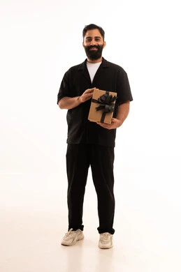 بورتريه لرجل عربي خليجي عماني يرتدي الزي الكاجوال يحمل صندوق هدية ينظر بايماءات السعادة، مفهوم الشكر والامتنان، تقديم الهدايا بالاعياد والمناسبات الخاصة، التعبير عن الحب والتقدير والاحترام، الجسم بالطول الكامل، خلفية بيضاء