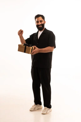 مفهوم الشكر والامتنان، تقديم الهدايا بالاعياد والمناسبات الخاصة، التعبير عن الحب والتقدير والاحترام، بورتريه لرجل عربي خليجي عماني يرتدي الزي الكاجوال يحمل صندوق هدية ينظر بايماءات السعادة، الجسم بالطول الكامل، خلفية بيضاء