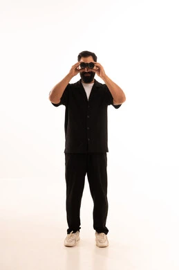 A portrait of a young Arab Gulf Omani man wearing casual attire, looking through binoculars, pointing with his index finger at something with gestures of joy and happiness, seeing distant things through the binoculars, a love for adventure and exploration, with a white background.