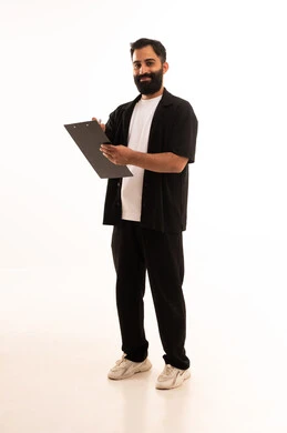 تسجيل الملاحظات والمعلومات المهمة, بورتريه لرجل عربي خليجي عماني يرتدي الزي الكاجوال يمسك بيديه سنادة ورق سوداء وقلم يقوم بكتابة شيء بإيماءات التركيز والتمعن، أدوات تدوين المهام اليومية، الجسم بالطول الكامل، خلفية بيضاء