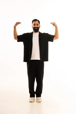 التمتع بالبنية الجسدية القوية، اللياقة البدنية والجسم الصحي المتين، بورتريه مقرب لرجل عربي خليجي عماني يرتدي الزي الكاجوال يقوم بعرض عضلات يديه ينظر الى الكاميرا بإيماءات القوة، صورة الجسم بالطول الكامل، خلفية بيضاء