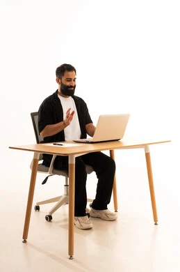 اجراء بث مباشر عبر الجهاز اللوحى  ، مشاهده الافلام والمسلسلات بتعابير السعاده ، دمج التقنيات الحديثة فى العمل، بورتريه لرجل عربي خليجي عماني يرتدي الزي الكاجوال يجلس على كرسي المكتب يعمل على جهاز الحاسوب المحمول ، خلفية بيضاء