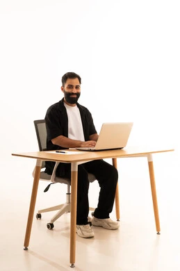 Integrating modern technologies into the administrative and office field, focusing on task completion, working in Omani offices and companies, a portrait of an Arab Gulf Omani man wearing casual attire sitting on an office chair working on a laptop, white background.