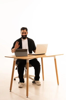 Conducting a live broadcast via the tablet, watching movies and series with expressions of happiness, integrating modern technologies in work, a portrait of an Arab Gulf Omani man wearing casual attire sitting on an office chair working on a laptop, white background.