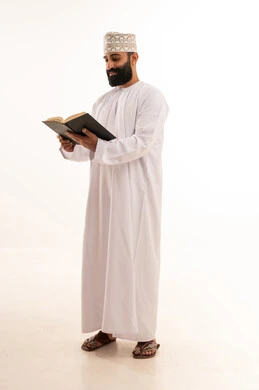 الاستمتاع بقراءة الروايات والقصص، قراءة الكتب بتمعن، ثقافة التعلم الذاتي ، بورترية لشاب عربي خليجي عماني يرتدي الدشداشة و الكمة يمسك بيده كتاب تثقيفي ، خلفية بيضاء