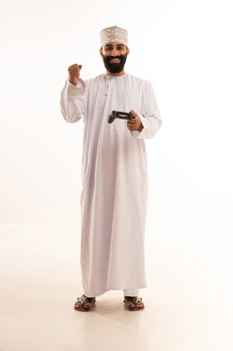 Expressions of victory and triumph, enjoying fun times in recreational video games, a portrait of an Arab Gulf Omani boy wearing a dishdasha and kumma holding a game controller in his hand, gestures of enjoyment and immersion, using technological devices and modern techniques, white background.