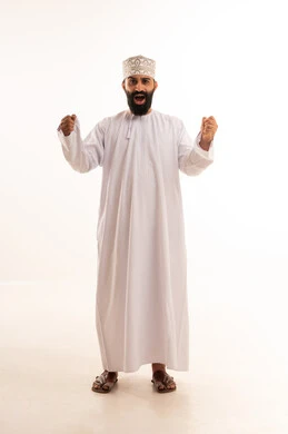 إيماءات الفرح والنصر لسماع خبر ما, النظر الى الكاميرا بتعابير الفوز و تحقيق الأهداف، بورتريه لرجل عربي خليجي عماني يرتدي الدشداشة والكمة يرفع يديه بحركات الحماس و السعادة, الجسم بالطول الكامل, خلفية بيضاء