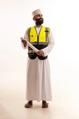 The concept of architectural constructions, a portrait of an Arab Gulf Omani engineer wearing a dishdasha and a kumma and a safety vest holding a plan in his hands, working in the field of engineering, a profession and job for youth in the Sultanate of Oman, supervising engineering project plans, full-body, white background.