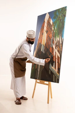 أنشطة ترفيهية فنية ممتعة، استخدام ريشة التلوين، بورتريه لرسام عربي خليجي عماني يرتدي الدشداشة والكمة وقبعة يحمل بيديه الالوان المائية, ورشة عمل وفنون, خلفية بيضاء