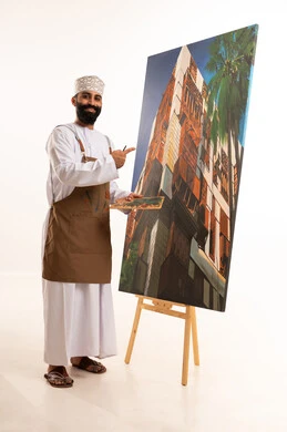 ورشة عمل وفنون, استخدام ريشة التلوين، أنشطة ترفيهية فنية ممتعة، بورتريه لرسام عربي خليجي عماني يرتدي الدشداشة والكمة وقبعة يحمل بيديه الالوان المائية,خلفية بيضاء