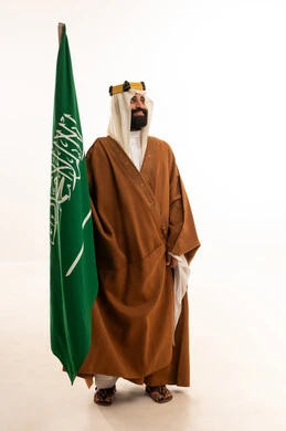 The anniversary of the establishment of the first Saudi state is on February 22, the day we began in 1727 AD. The commemoration of the Saudi National Day is on September 23. A portrait of an Arab Saudi Gulf man wearing a bisht, ghutrah, and agal on the day of establishment, raising the Saudi flag. Flag Day is on March 11, with a white background.