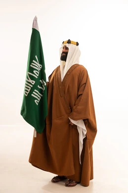 يوم العلم ١١ مارس ، ذكرى تأسيس الدولة السعودية الأولى في 22 فبراير، يوم بدينا 1727م ، تذكار اليوم الوطني السعودي 23 سبتمبر، بورتريه لرجل عربي سعودي خليجي يرتدي البشت والغتره وعقال يوم التأسيس يرفع علم السعوديه, خلفية بيضاء