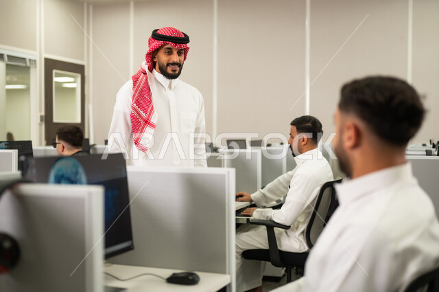 استخدام الحاسوب للتعلم المدرسى، مجموعة من الطلاب العرب الخليجيين السعوديين يرتدون الثوب التقليدى يجلسون أمام أجهزة الكمبيوتر في مختبر حديث، التعليم فى السعودية, مجموعة من الموظفين  يعملون أمام أجهزة الحاسوب