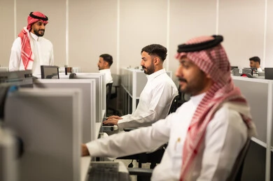 Paying attention, focusing, and listening to the lecture: A Saudi Arabian Gulf Arab university professor, wearing a traditional thobe and shemagh, trains his students in a computer lab. Education in Saudi Arabia. A group of Saudi Arabian Gulf Arab employees work at the company headquarters.