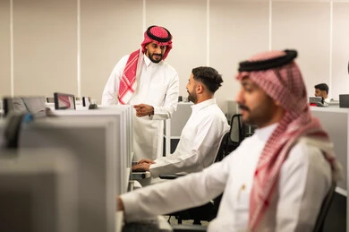 تبادل الأحاديث ضمن مقر الشركة، التعليم فى المملكة العربية السعودية,استخدام الأجهزة التقنية الحديثة معلم  يقوم بالشرح لطلابه, مجموعة من الموظفين العرب الخليجيين السعوديين يرتدون الثوب التقليدى يعملون أمام أجهزة الحاسوب في مقر الشركة