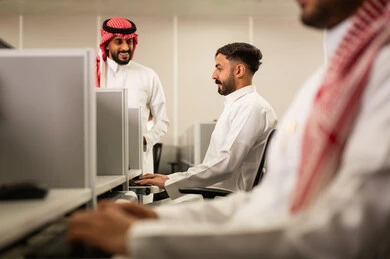 مفهوم تدريب وتطوير الموظفين، التعليم فى المملكة العربية السعودية, طلاب عرب يجلسون أمام أجهزة الكومبيوتر في مختبر  الحاسوب, مجموعة من الموظفين العرب الخليجيين السعوديين يرتدون الثوب التقليدى يعملون أمام أجهزة الحاسوب في مقر الشركة
