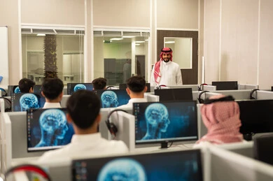 Integrating modern technology into working life: A group of Saudi Arabian Gulf employees wearing traditional attire work at computers in the company headquarters; Arab students sit at computers in a modern lab; Education in Saudi Arabia