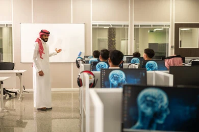 استخدام جهاز تقني حديث في التعلم والدراسة داخل الفصل الدراسي, مجموعة من الموظفين العربيين الخليجيين السعوديين يرتدون الثوب التقليدى يعملون أمام أجهزة الحاسوب في مقر الشركة, معلم عربي خليجي سعودى يقوم بشرح الدرس