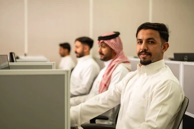 تعابير الثقة بالنفس، ارتداء سماعة الرأس والعمل على جهاز الحاسوب في خدمة العملاء في مقر الشركة, التعليم فى المملكة العربية السعودية,  طلاب عرب يجلسون أمام أجهزة الكومبيوتر في المختبر