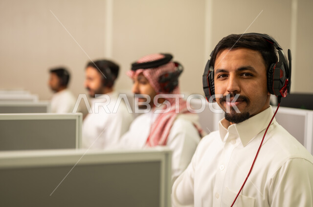 تعابير و إيماءات الثقة بالنفس, موظف عربى خليجى سعودى يرتدى الثوب التقليدى يعمل أمام جهاز الحاسوب في مقر الشركة,استخدام تقنية الهيدفون, طلاب عرب يجلسون أمام أجهزة الكومبيوتر في مختبر حديث, التعليم فى المملكة العربية السعودية
